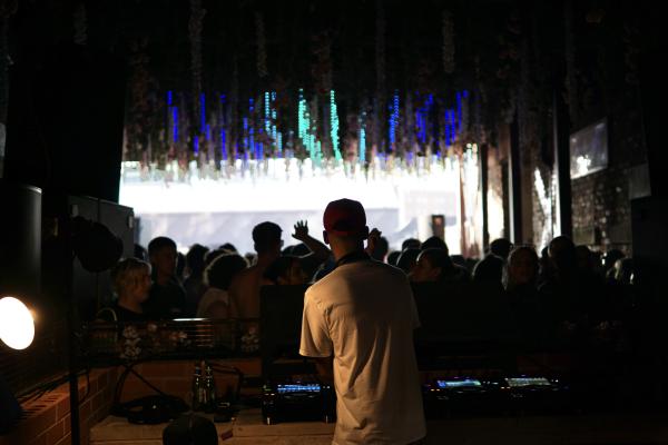 Miguel Campbell on the decks looking out into the crowd from behind.